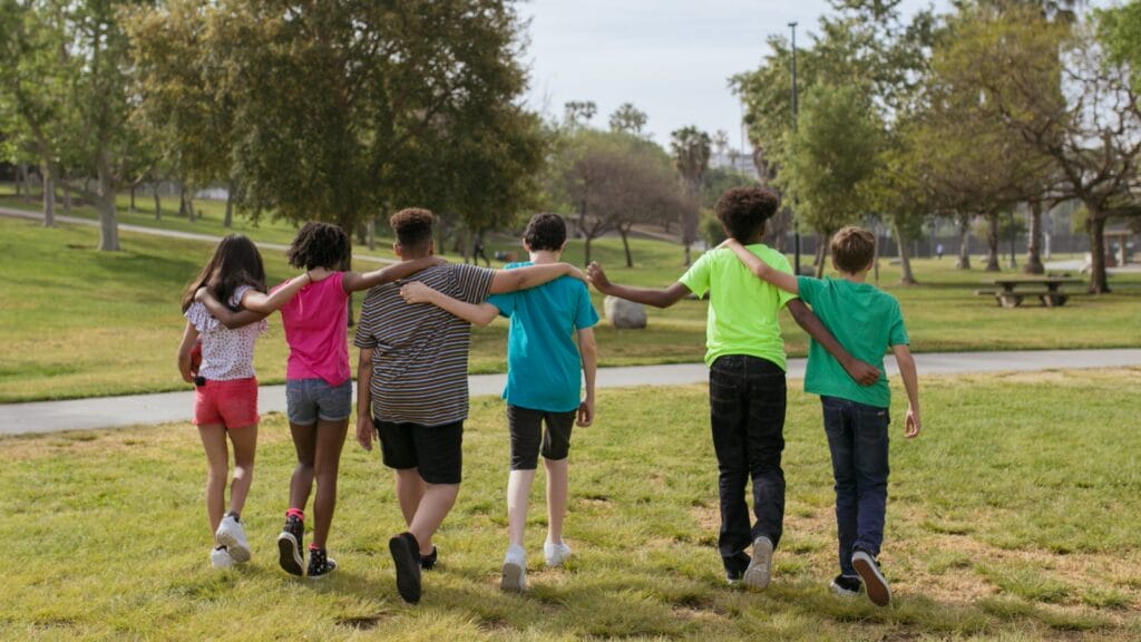 children hugging each other walking through a park
