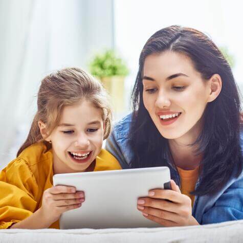 mom and girl looking the ipad and smiling